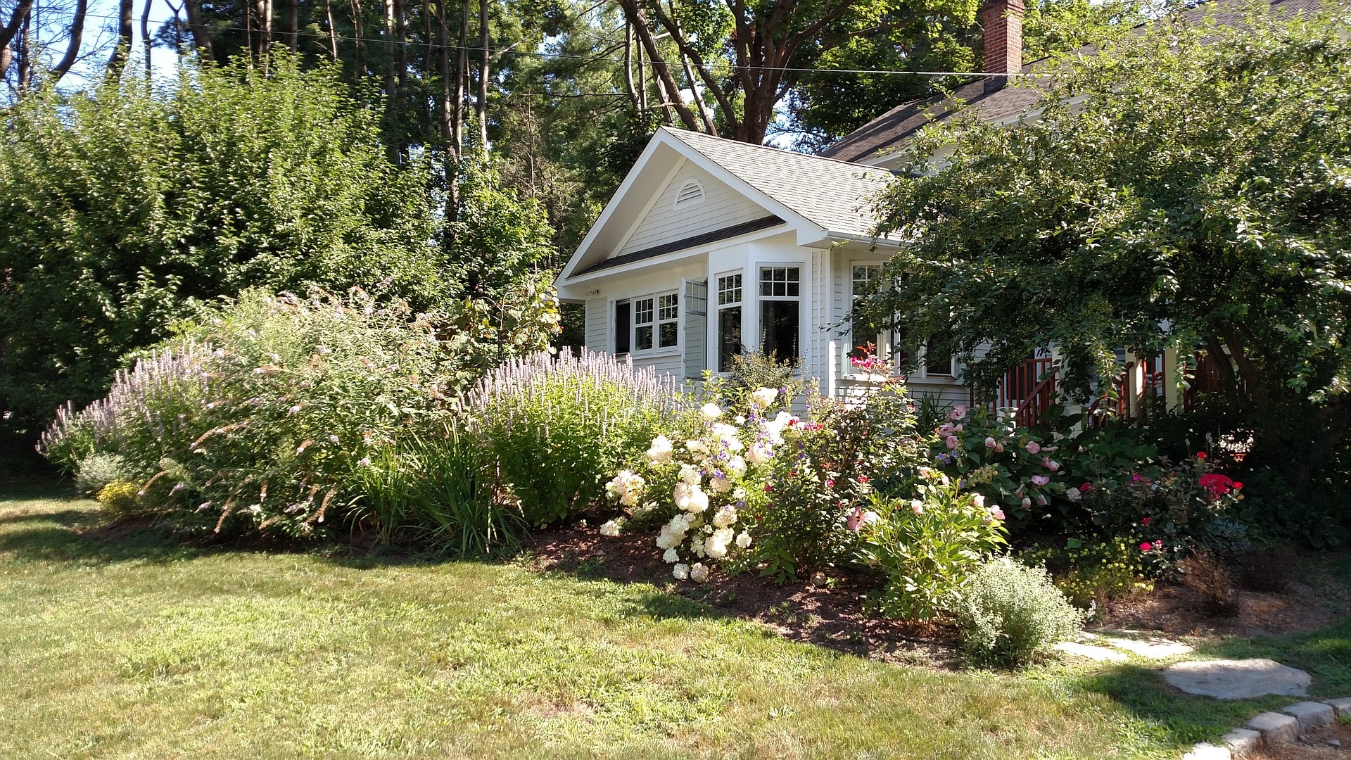 Maison avec jardin fleuri et arbustes sous un temps ensoleillé